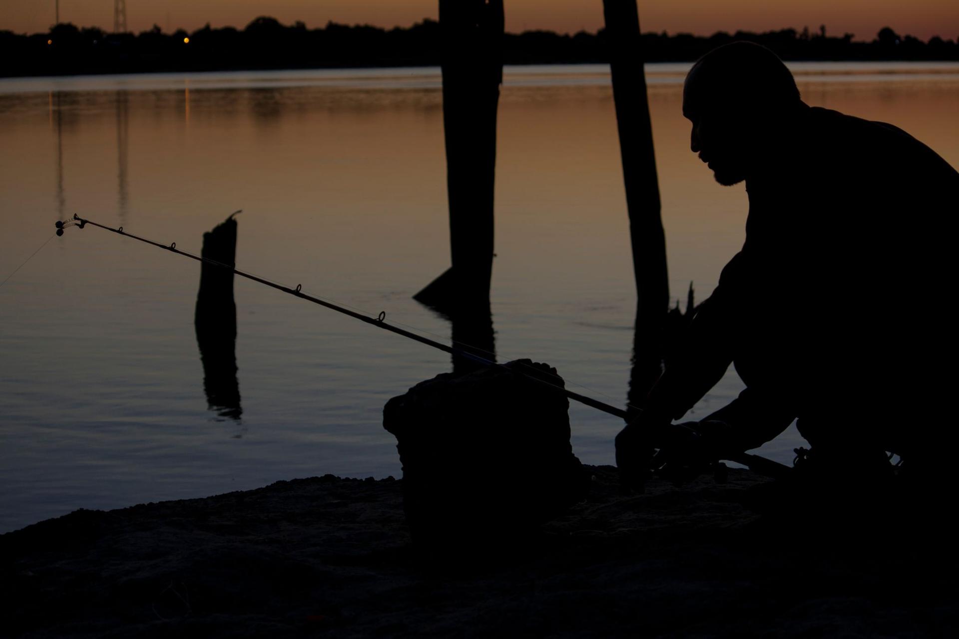 Angler in der Dämmerung am Wasser